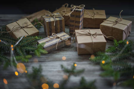 Christmas background. Gift boxes wrapped in craft paper, fir branches and garland lights.の写真素材