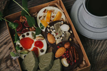 Chocolates with dried fruits in a craft box and a cup of espresso coffee.の写真素材