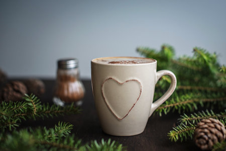 Christmas coffee with cinnamon on a wooden table. Spruce branches and cones, chocolate spoon. Winter mood.の写真素材