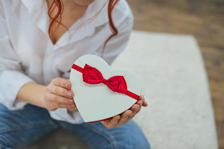A girl with a haircut in bunches in a white shirt with a gift box in her hands.の写真素材