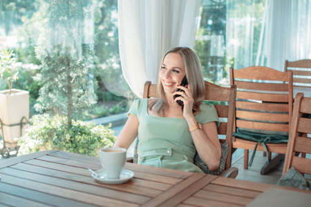 An attractive woman at a table in a cafe communicates on a smartphone.の写真素材