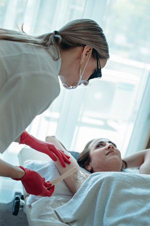 A woman beautician makes a diode laser epilation procedure.の写真素材