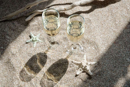 Two glasses of champagne against background with sand and starfish. The trendy color of champagne.の写真素材