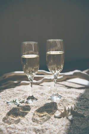 Two glasses of champagne against background with sand and starfish. The trendy color of champagne.の写真素材