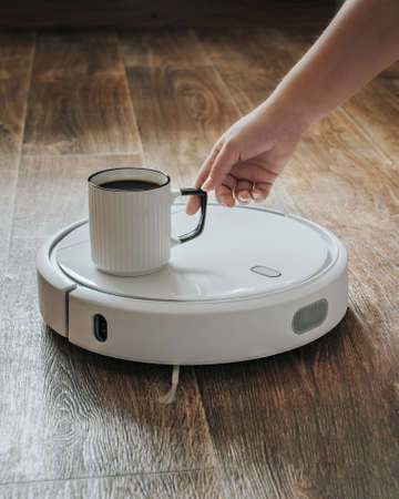 A robot vacuum cleaner brought a cup of coffee.の写真素材