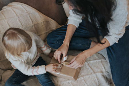Little girl and her mother open a Christmas present.の写真素材