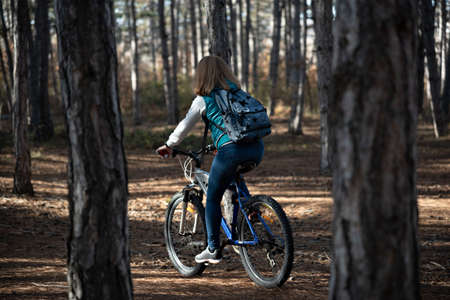 A young woman is riding a mountain bike in a pine forest.の写真素材