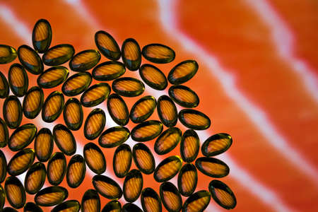 Fish oil omega 3 transparent capsules on the background of salmon fillet.の写真素材