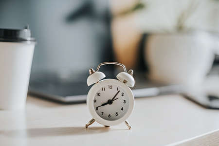 White alarm clock on the desktop in the officeの写真素材