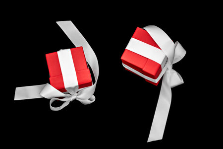 Two red gift boxes with white bows levitate on a black background.