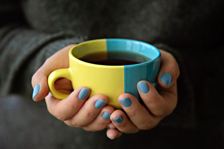A mug in the colors of the Ukrainian flag in hands.の写真素材
