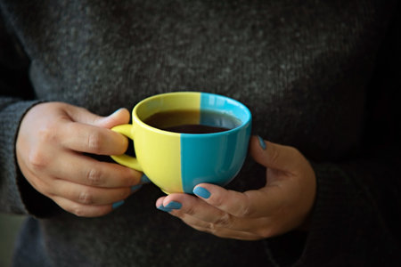 A mug in the colors of the Ukrainian flag in hands.の写真素材