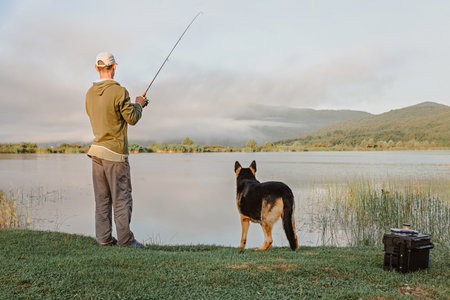A man and dog are fishing on the lake in the morning.の写真素材