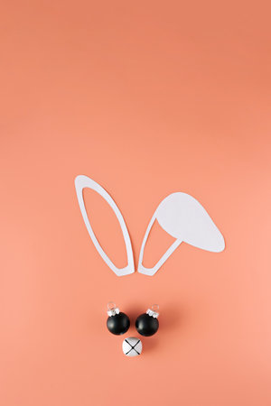 Minimalistic Christmas composition. Bunny face made from paper ears, Christmas bell and balls.の写真素材
