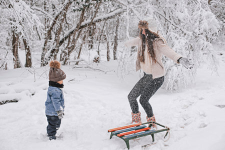 Mom and son are walking in the snow in the forest.の写真素材