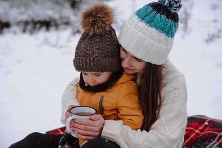 Mother and child on a winter walk outdoors drinking teaの写真素材