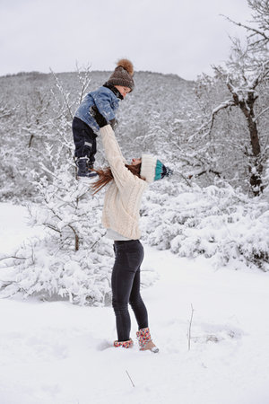 Mom and son are walking in the snow in the forest.の写真素材
