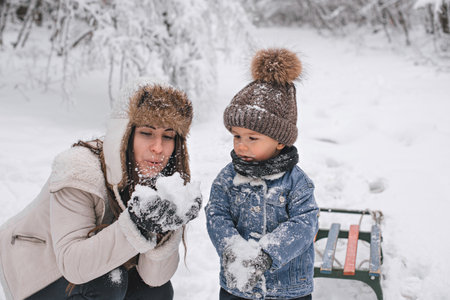 Mom and son are walking in the snow in the forest.の写真素材