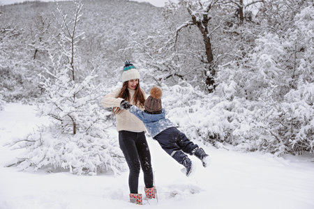 Mom and son are walking in the snow in the forest.の写真素材