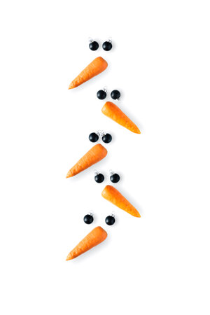 Creative snowman faces made of carrots and black Christmas balls in shape of christmas tree on a white background.の写真素材