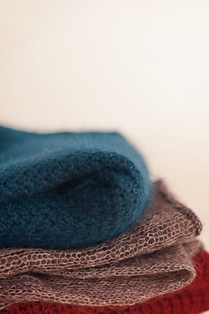 A stack of multi-colored knitted woolen products lies on a wooden stool