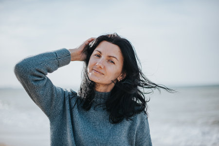 A middle-aged woman of natural appearance without makeup against the background of the sky and the sea. Natural appearance, first wrinkles, pigmentation on the skin.の写真素材