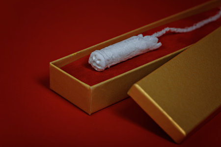 Women's hygienic tampon in a golden gift box on a red background. Creative concept Menstruation is not a luxury.の写真素材