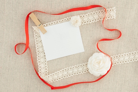 Valentine, blank, greeting card with red ribbon, white roses and pin.の写真素材