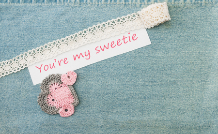 Valentine greeting card with three crocheted pink hearts and  lettering You%u2019re my sweetie on the denim background.の写真素材