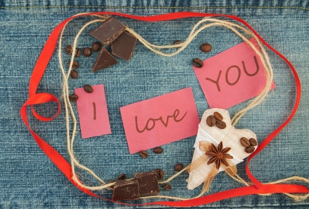 Valentine, greeting card with  brown coffee hearts, red ribbon, coffee, chokolate on the denim background. Handmade concept. Lettering I love youの写真素材