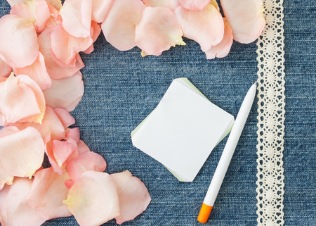 Valentine's day  background. Denim blue background with soft pink rose petals, paper and pen.の写真素材