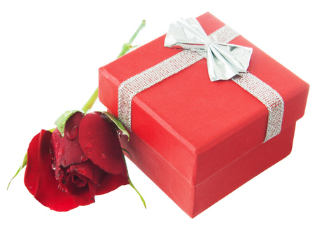 Red greeting box with silver ribbon,bow and little red rose near. Isolated white backgroundの写真素材