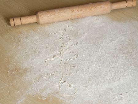 Valentine background, greeting card. Meal white hearts, wheat meal, rolling-pin on the desk.  Your text on the cardの写真素材