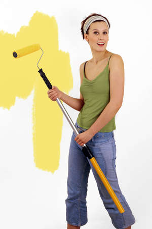 Woman painting on wall using paint rollerの写真素材
