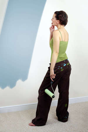 Woman painting on wall using paint rollerの写真素材