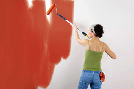 Woman painting on wall using paint rollerの写真素材