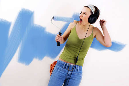 Woman painting on wall using paint rollerの写真素材