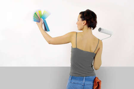 Woman painting on wall using paint rollerの写真素材