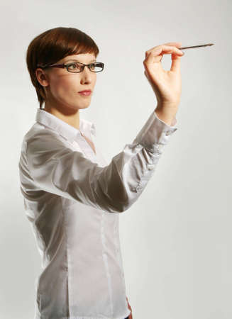 Young woman wearing glasses, holding up pen の写真素材
