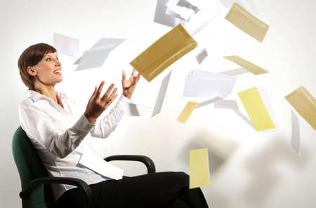 Young business woman on chair, throwing letters in air, smilingの写真素材