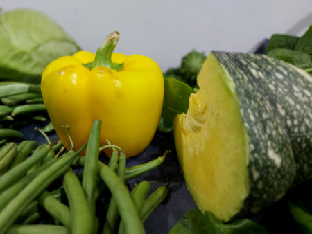 a yellow capsicum and a sliced pumpkin kept with other vegetables