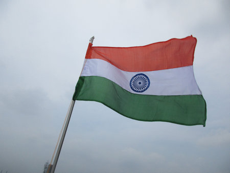 close up view of an indian flag flying high in the winds with blue sky in the background