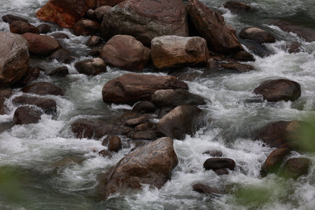 close up scenic view of water ghushing through big stones in the mountainsiの写真素材