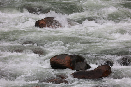 close up scenic view of water ghushing through big stones in the mountainsの写真素材