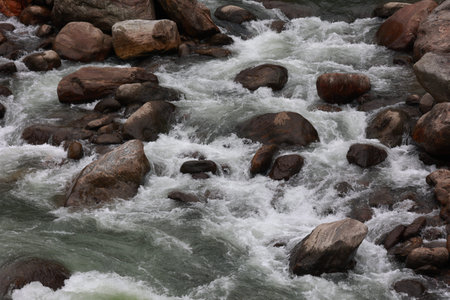 close up scenic view of water ghushing through big stones in the mountains
