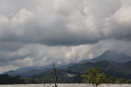 Clouds over a mountain landscape with a river in the foreground. Copy space for text