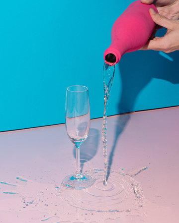 Cute party scene with pink champagne bottle and glass. Minimal party concept with copy space. Pastel...
