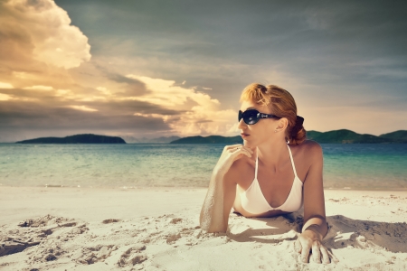 A pretty woman in bikini sunbathing at the beach on a background of the islands の写真素材