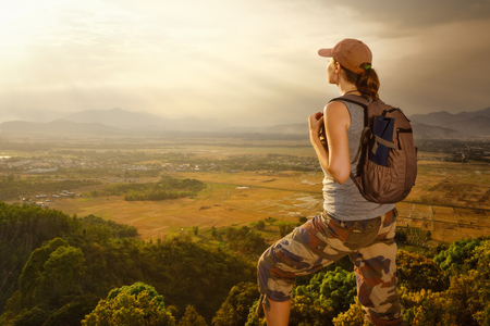 Traveler with backpack relaxing on top of a mountain and enjoying valley view during sunset.Mountains landscape, travel to Asia, happiness emotion, summer holiday conceptの写真素材