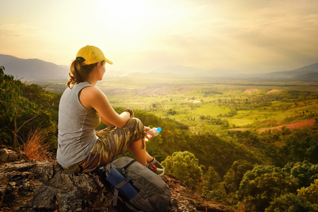 Portrait of woman with backpacker sitting on top of the mountain and enjoying sunset.Mountains landscape, travel to Asia, happiness emotion, summer hike concept.の写真素材
